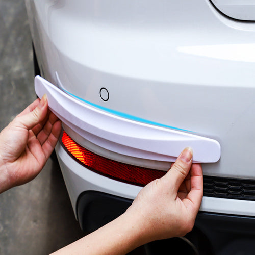 Hands fitting a white KZ Bumper Guard Strip to the rear bumper of a white car